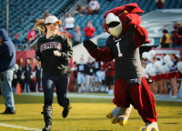 Kelly Dougherty, the winner of TUTV's Most Spirited Contest is shown running on to the football field with Hooter the Owl