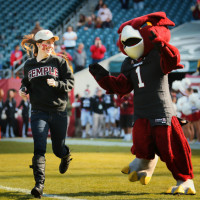 Kelly Dougherty, the winner of TUTV's Most Spirited Contest is shown running on to the football field with Hooter the Owl