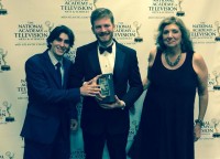 Faculty Advisor Fran Viola stands with student producers holding their Emmy award