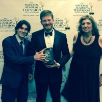 Faculty Advisor Fran Viola stands with student producers holding their Emmy award